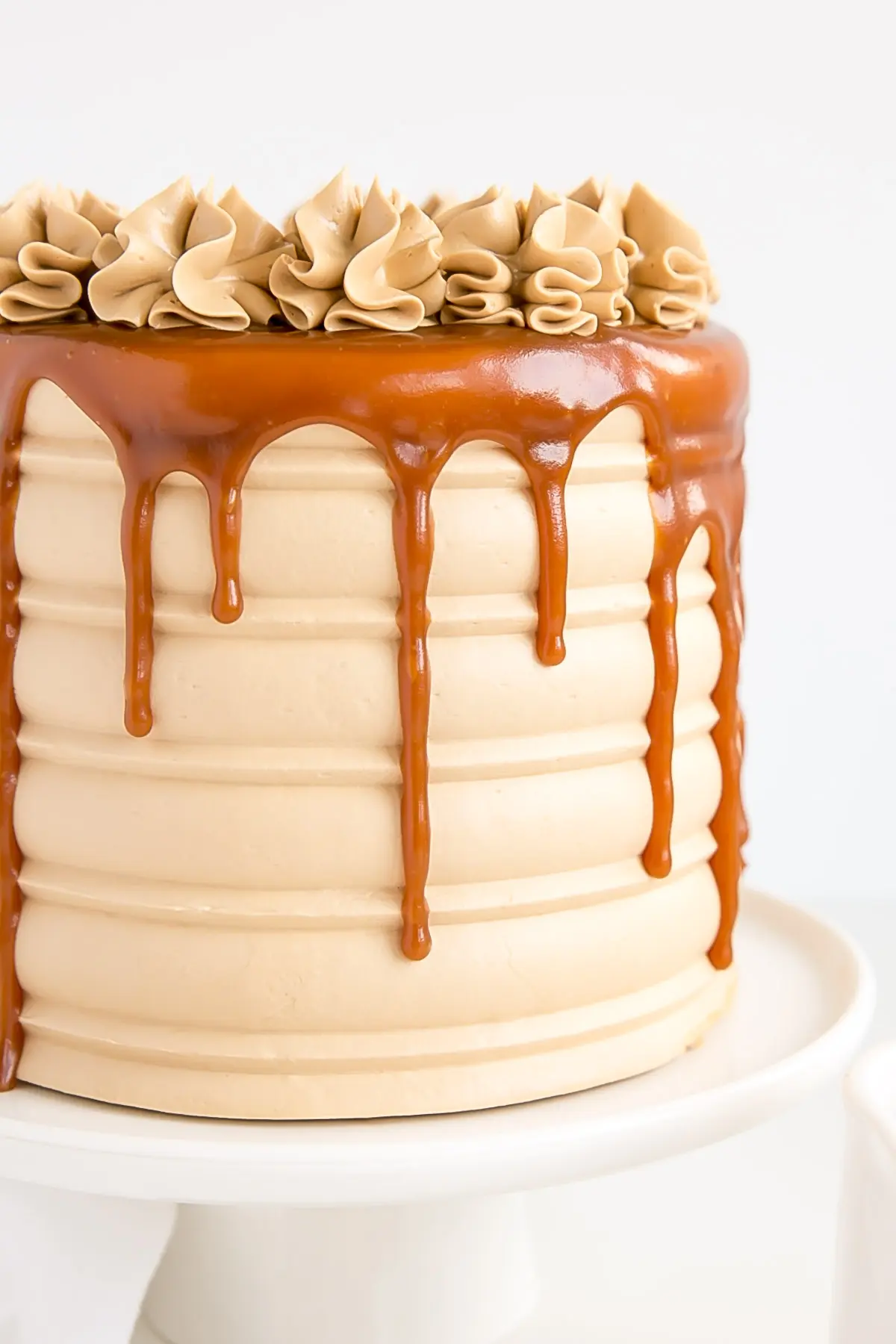 Close up of a caramel cake showing textured sides and a caramel drip.