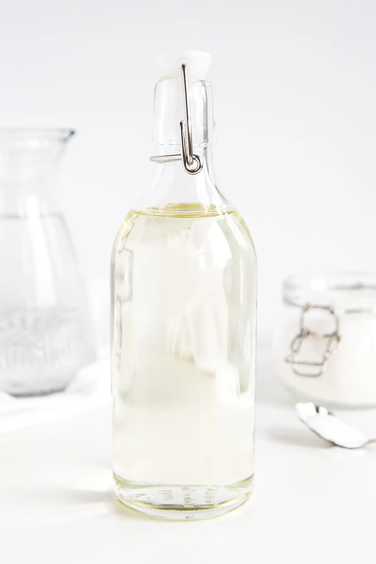 A bottle of homemade simple syrup -- sugar and water in the background.