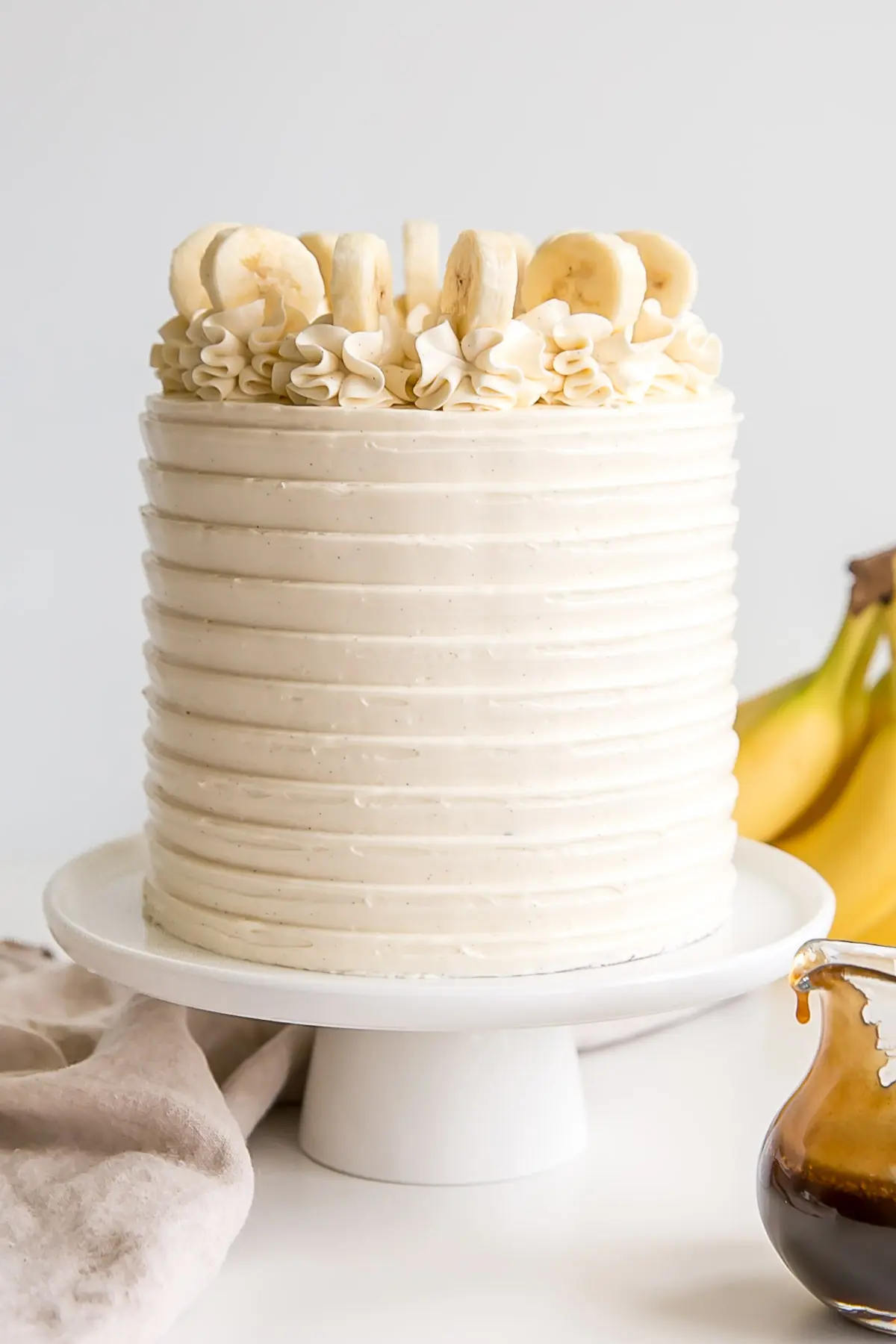 Vanilla bean frosting covered cake with rosettes on top and fresh banana slices.