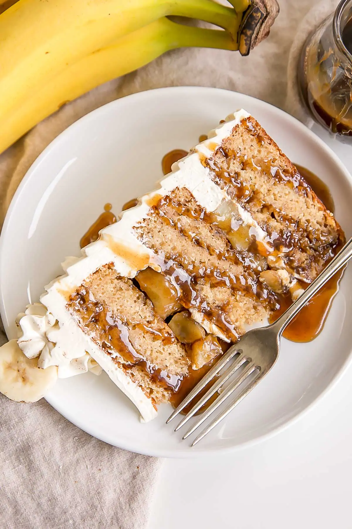 Slice of Bananas Foster Cake on a plate drizzled with Fosters sauce.