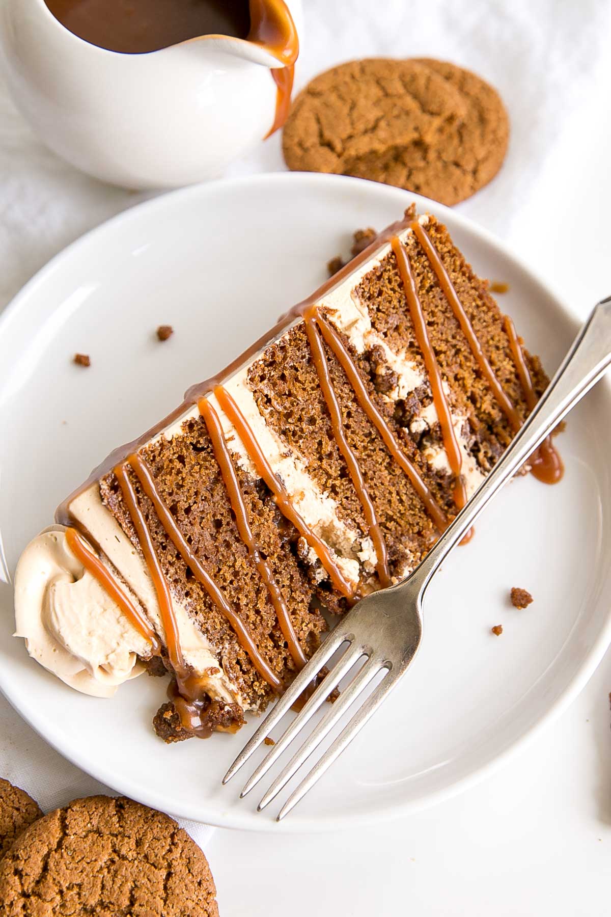 Slice of gingerbread cake on a plate with caramel drizzle over top.