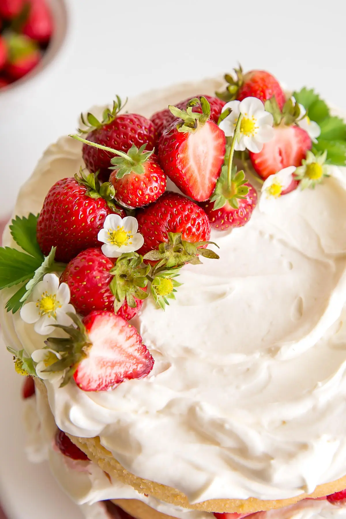 Fresh strawberries and strawberry flowers on top of mascarpone cream on the cake