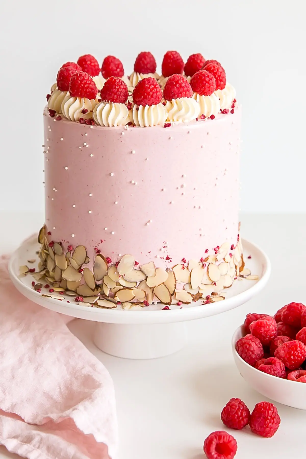 Bakewell cake decorated with almond slices and fresh raspberries.