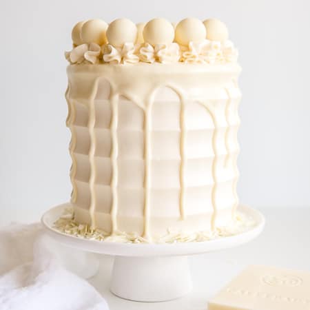 This White Chocolate Cake is both decadent and delicious! White chocolate is incorporated into the cake layers, the frosting, and the drip for a stunning monochrome effect.