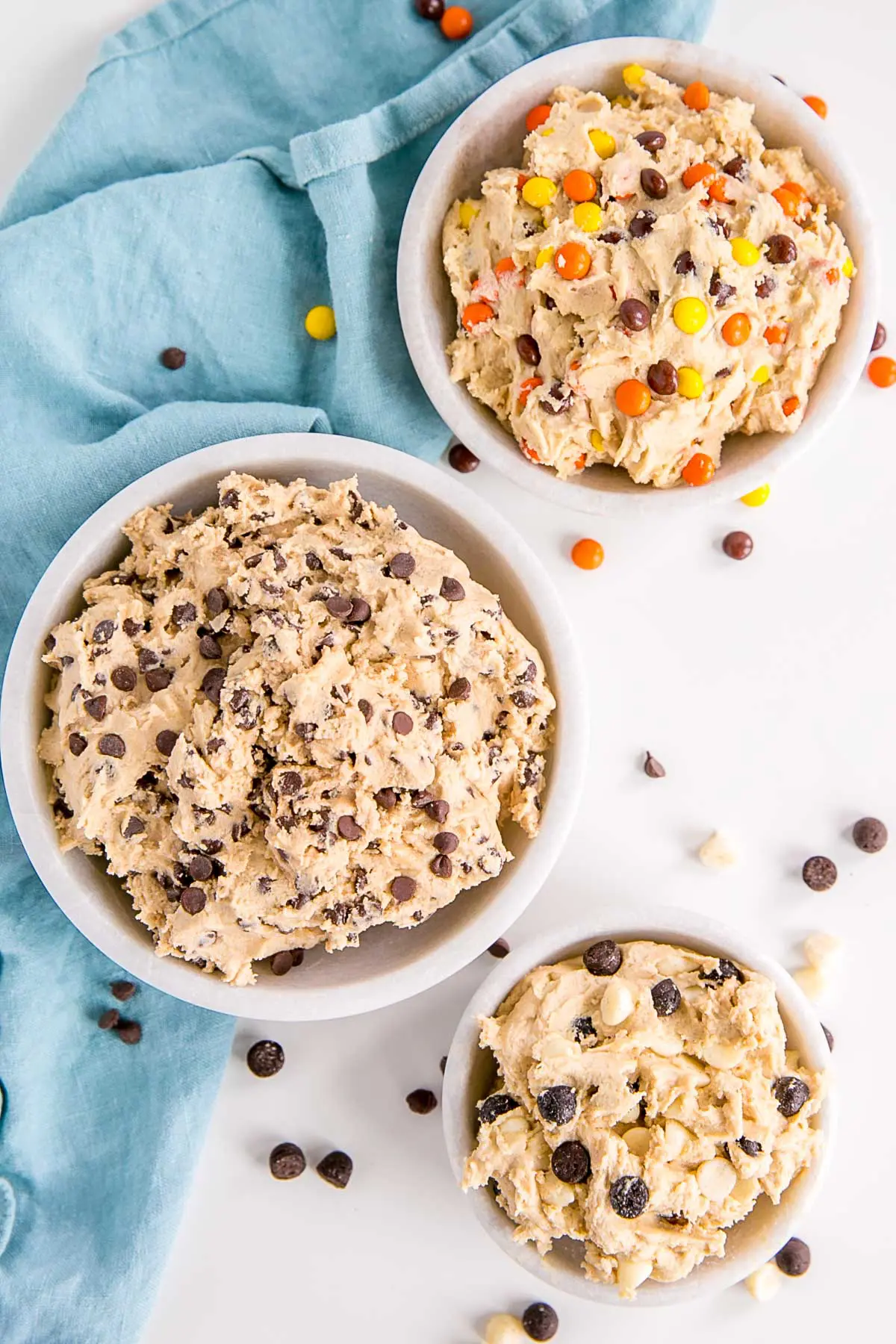 Three bowls of cookie dough each with different additions.