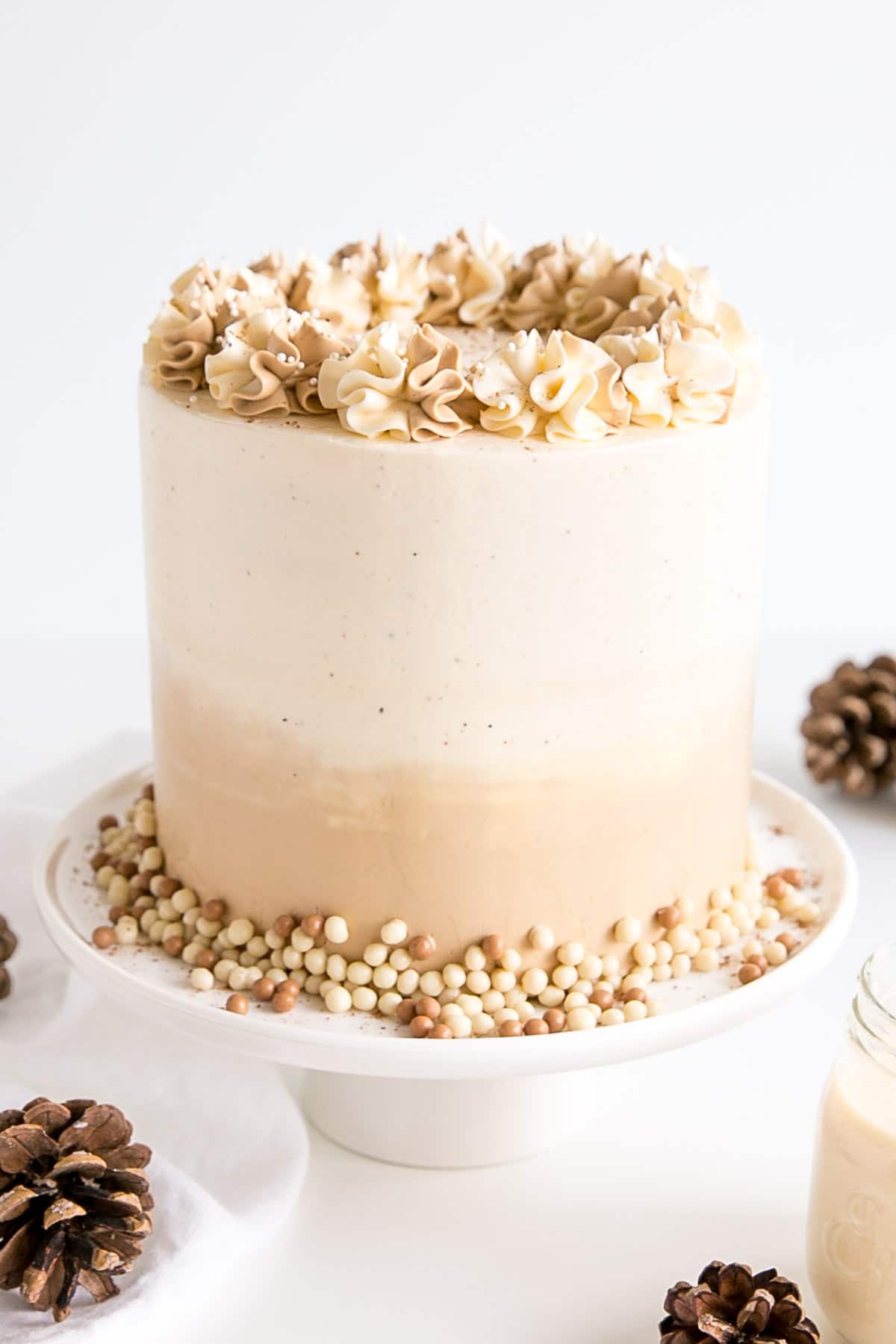 Slightly angled shot of the eggnog cake with pine cones in the foreground.