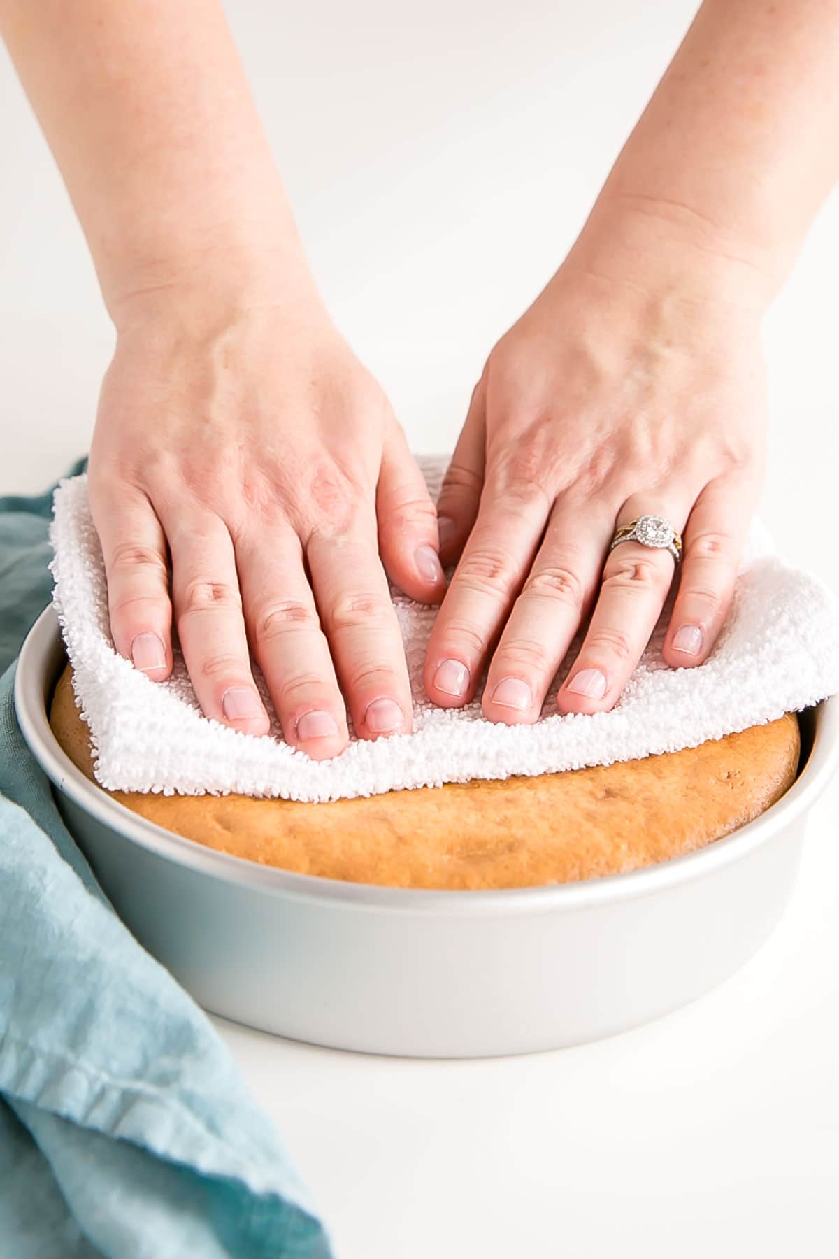 Pressing down on the top of a cake gently using a tea towel.