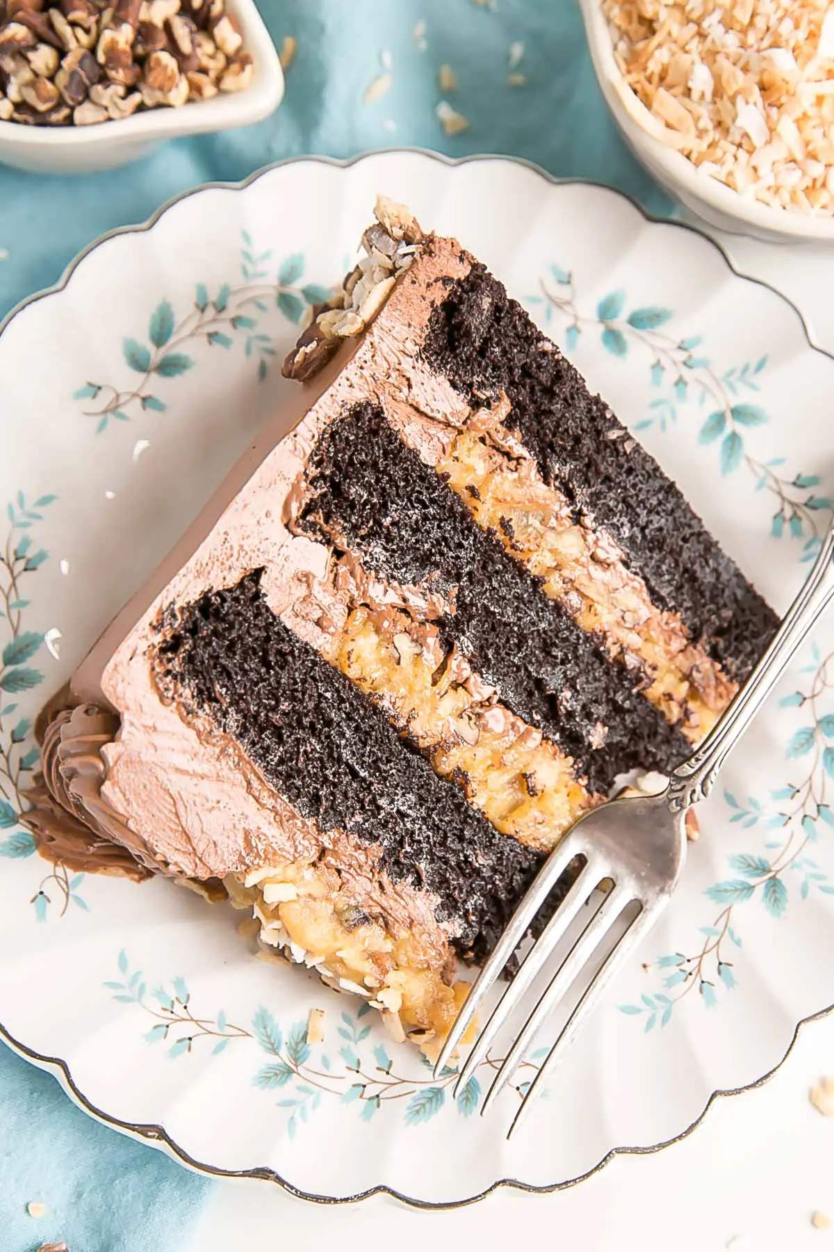 Une part de gâteau sur une assiette fleurie bleue avec un tissu bleu en dessous.