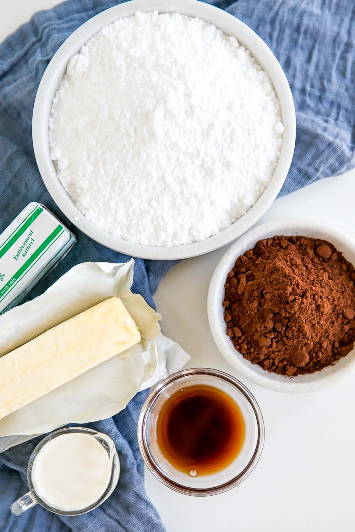 Chocolate buttercream ingredients laid out on a table with a blue cloth.